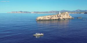 Vista del mar en Magaluf con un barco y una isla rocosa.