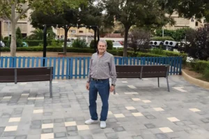 Esteban García en un parque de Sa Garriga, Mallorca, rodeado de bancos y árboles.