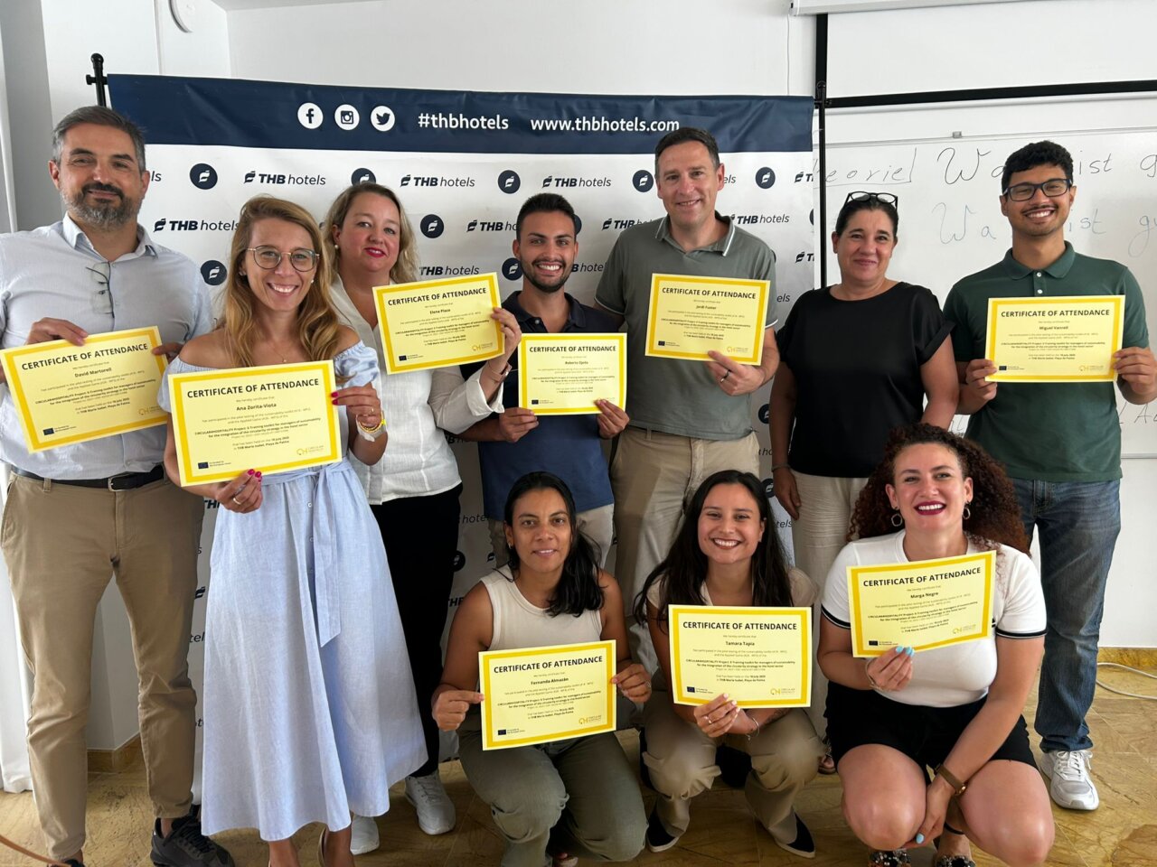 Grupo de participantes con certificados de asistencia en un taller de sostenibilidad hotelera en Mallorca.