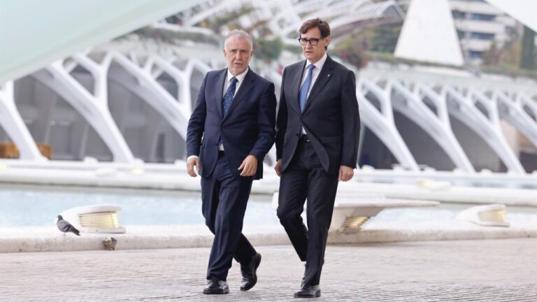 Dos hombres caminando junto a una estructura moderna en un entorno urbano.