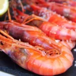 Gambas rojas frescas sobre una tabla con sal y limón