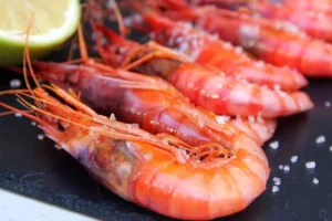 Gambas rojas frescas sobre una tabla con sal y limón