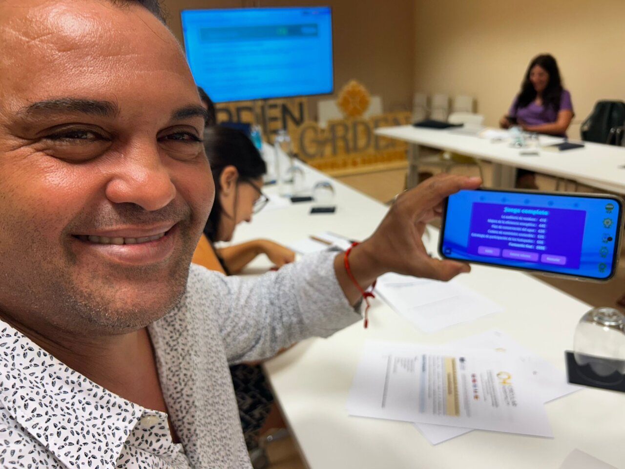 Persona sonriente mostrando un juego digital en un teléfono móvil.