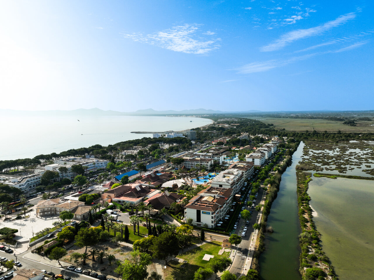 Vista aérea de la bahía de Alcudia en Mallorca con hoteles y naturaleza.
