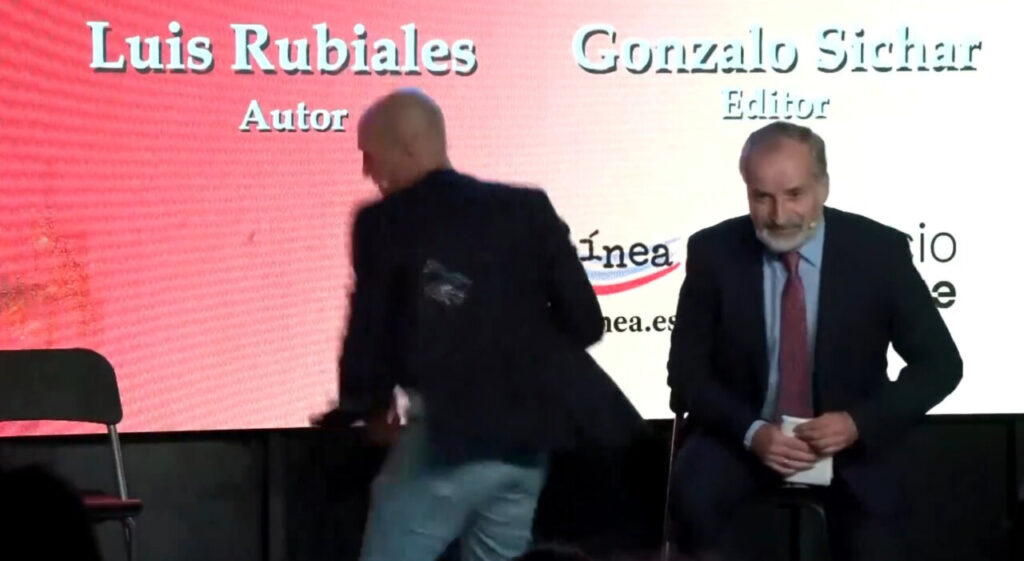 Luis Rubiales durante la presentación de su libro mientras un hombre lanza un huevo.