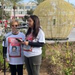 Dos mujeres hablando en un evento con carteles de Malen Ortiz.