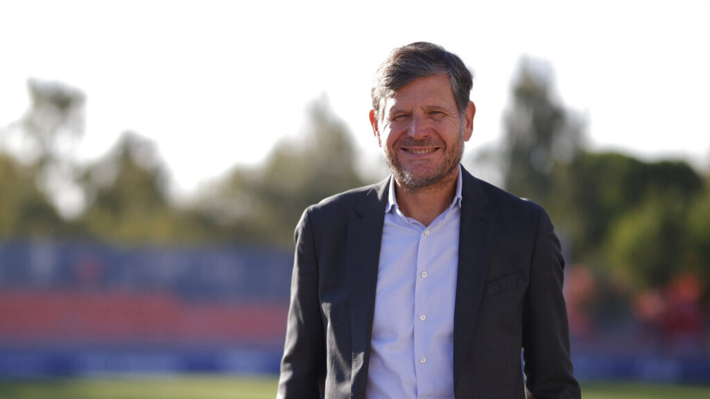 Hombre sonriente de pie en un estadio de fútbol