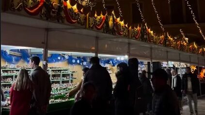 Personas visitando un mercado navideño iluminado en Mallorca
