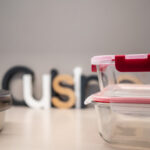 Tuppers de vidrio apilados sobre una mesa con letras decorativas.