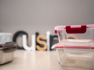 Tuppers de vidrio apilados sobre una mesa con letras decorativas.