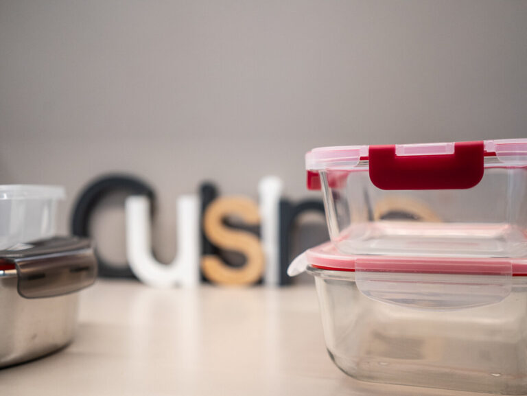 Tuppers de vidrio apilados sobre una mesa con letras decorativas.