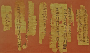 Fragmentos de papiro antiguo con escritura jeroglífica en fondo rojo.