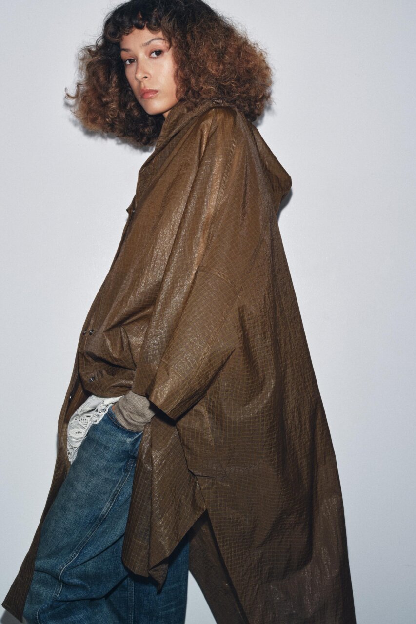 Modelo usando un poncho o capa impermeable en un fondo neutro