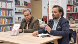 Dos hombres discutiendo sobre la novela El Caballero de la Ribera en una librer&iacute;a.