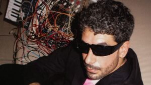 Artista de música electrónica con sintetizadores y actitud punk.
