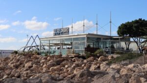 Vista del restaurante Varadero en el puerto de Palma con rocas y cielo azul