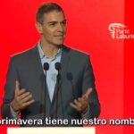 Pedro Sánchez hablando en un evento político con fondo rojo