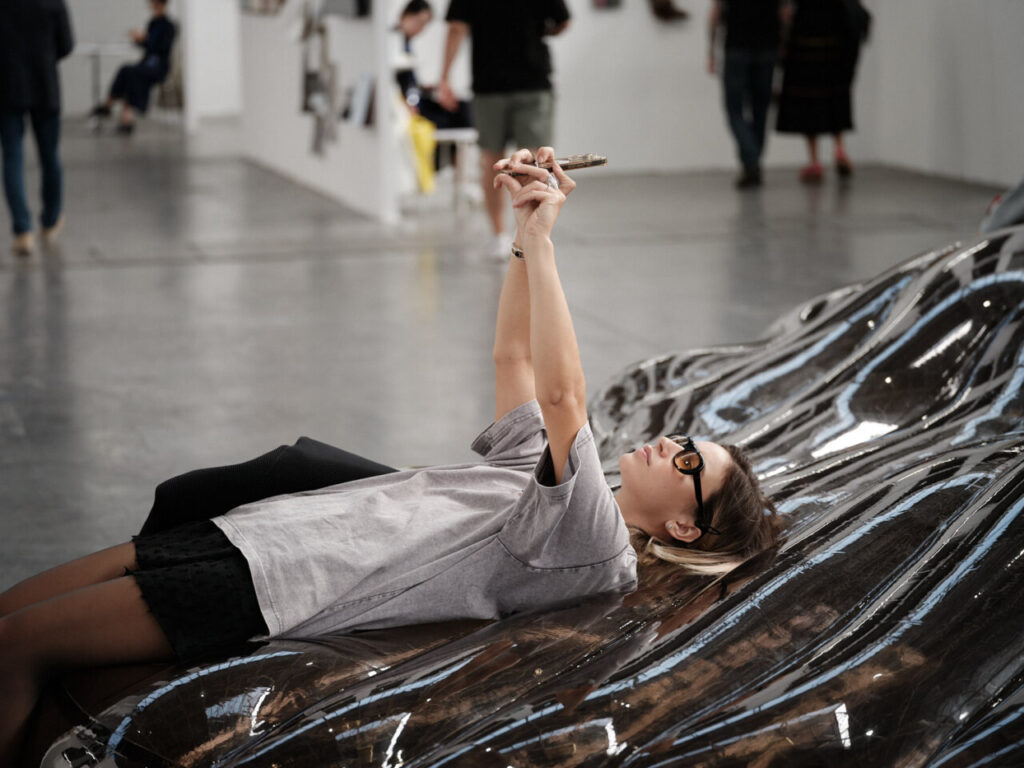 Una mujer descansando sobre una obra de arte en la feria Swab Barcelona 2025.