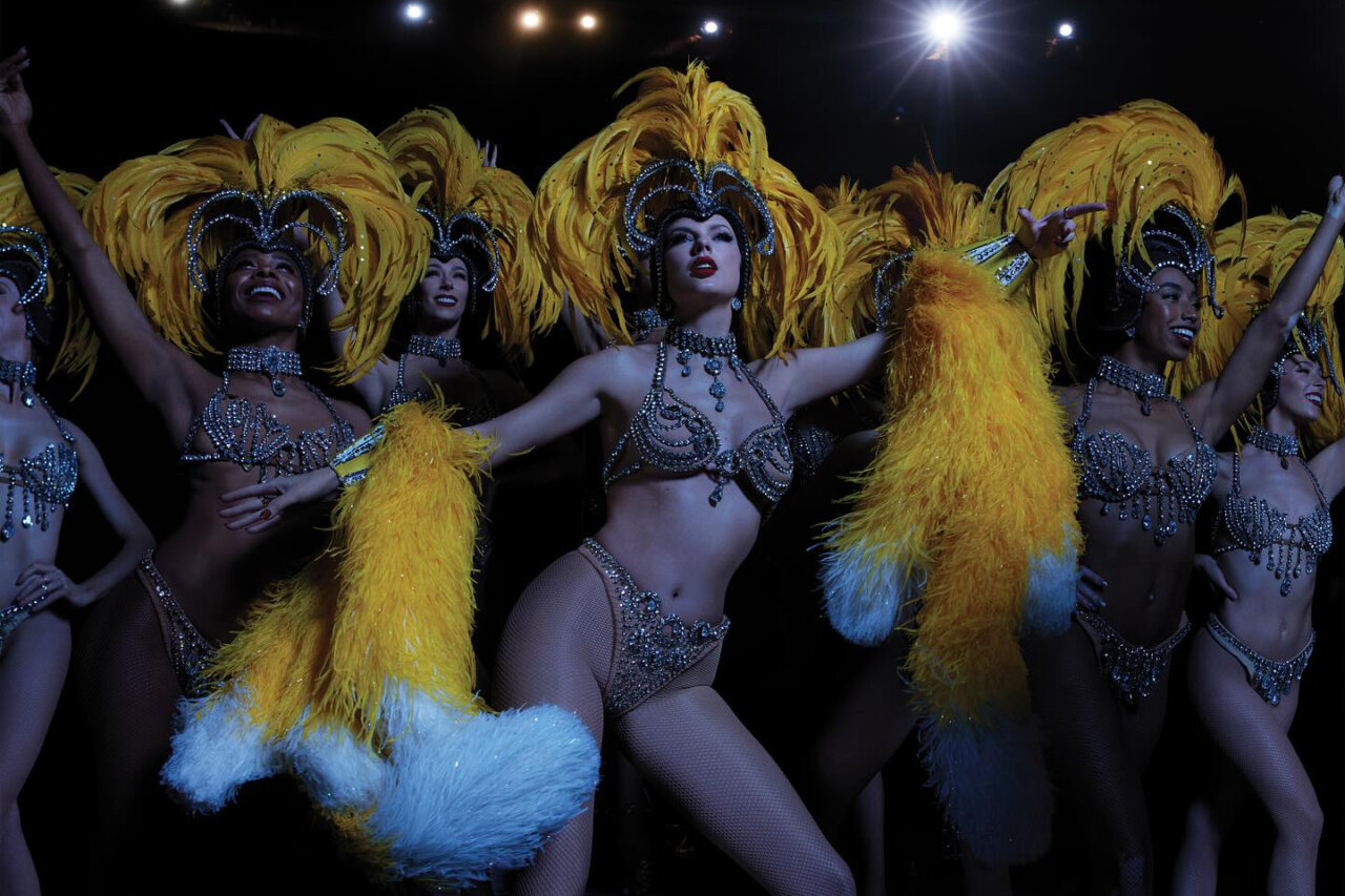 Taylor Swift en un espectáculo con bailarinas y plumas amarillas