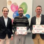 Tres hombres sosteniendo premios de reconocimiento en un evento