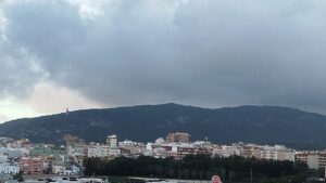 Vista de la ciudad con nubes y montañas en el fondo