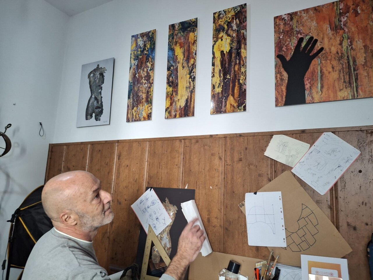 Toni Coll observando fotografías de sus esculturas en su estudio.