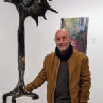 Toni Coll posando junto a una escultura en una galería de arte