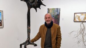 Toni Coll posando junto a una escultura en una galería de arte