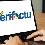 Persona usando un ordenador portátil con el logo de Verifactu en la pantalla.