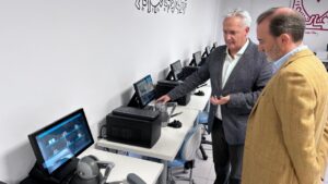 Dos hombres observando simuladores virtuales en un aula moderna.