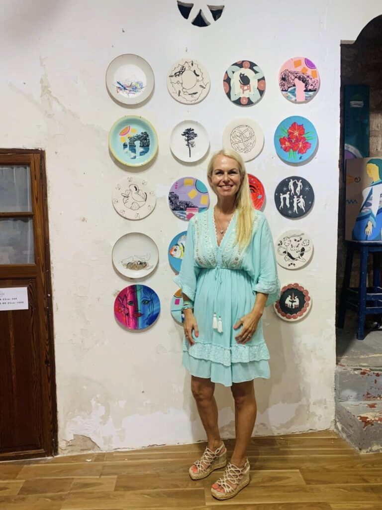 Yvonne Erdmann posando frente a platos decorativos en una pared.