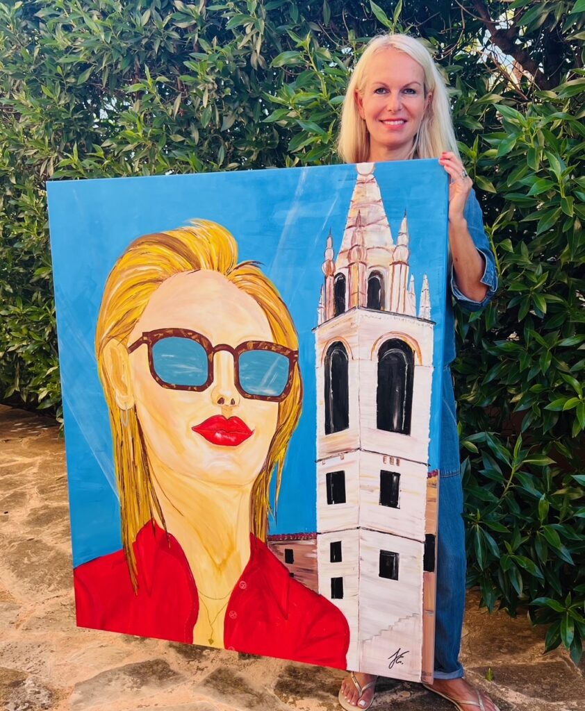 Yvonne Erdmann sosteniendo su pintura junto a un edificio