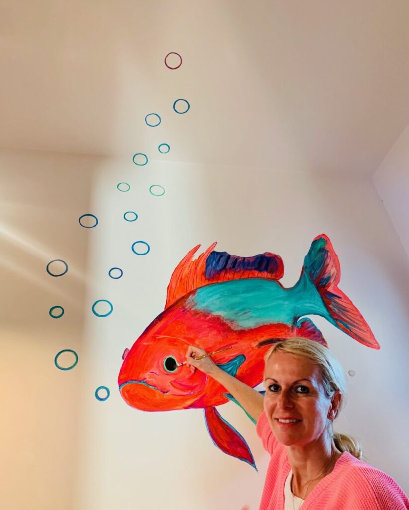 Yvonne Erdmann pintando un pez colorido en la pared