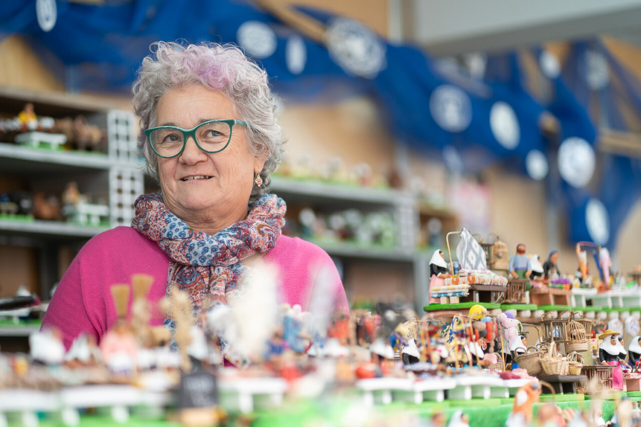 Mujer sonriendo entre artesanías navideñas en un mercado.