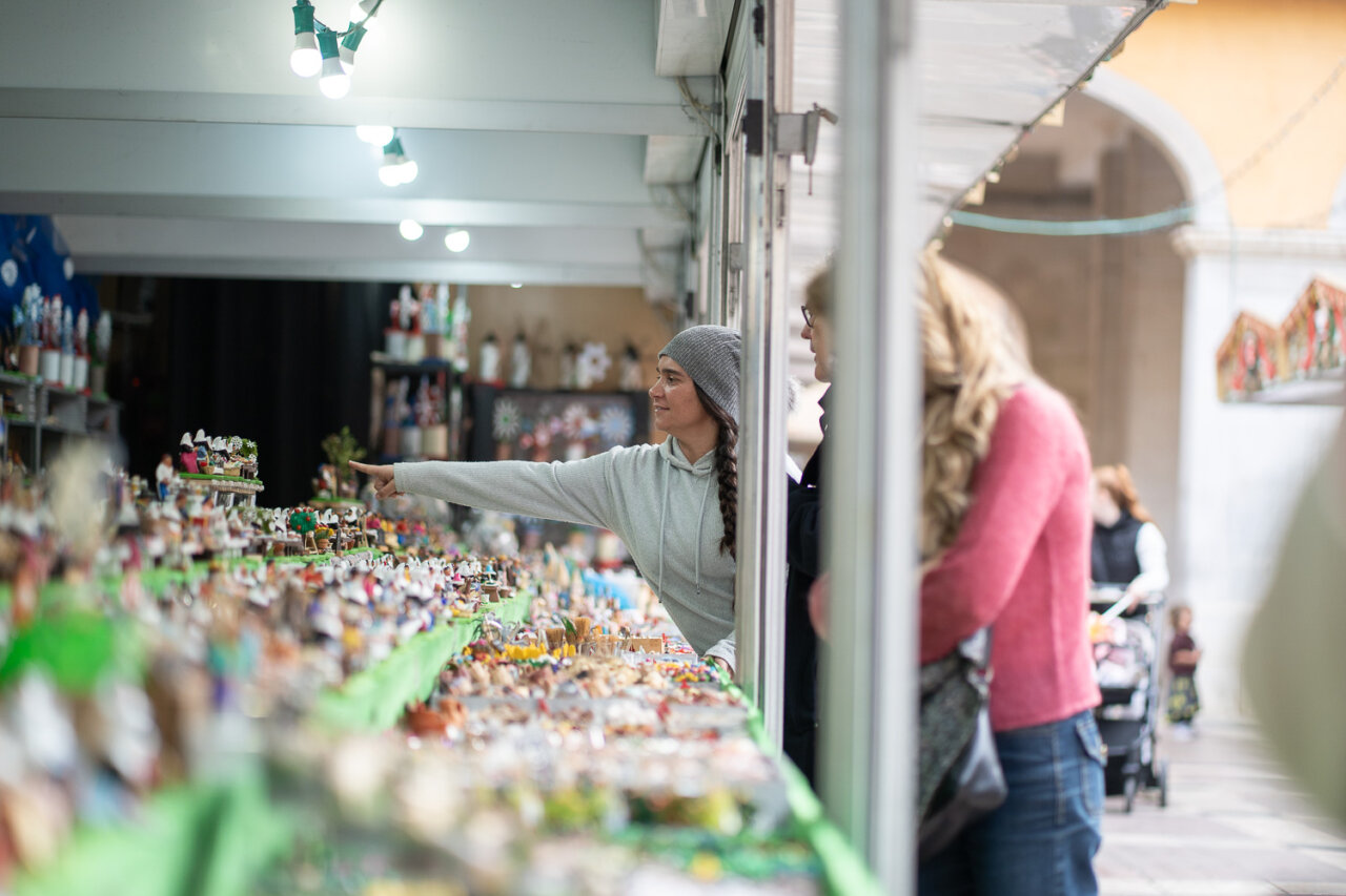 Mujer señalando artesanías en un mercado navideño