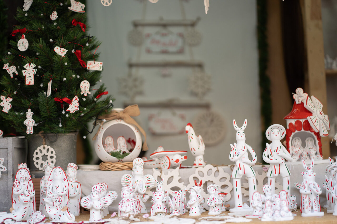 Decoraciones navideñas artesanales en una plaza con árbol y figuras.