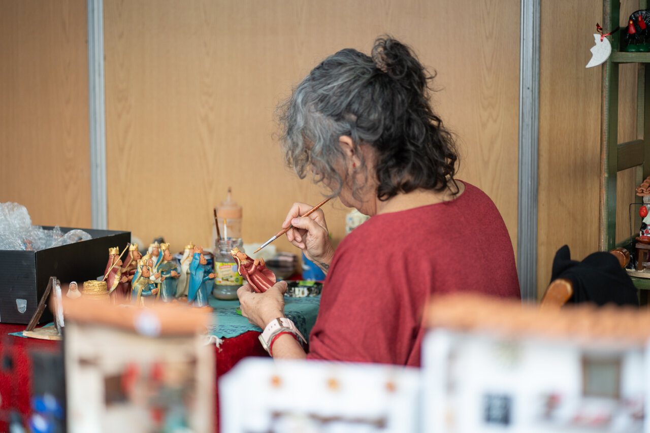 Mujer pintando figuras artesanales en un mercado navideño