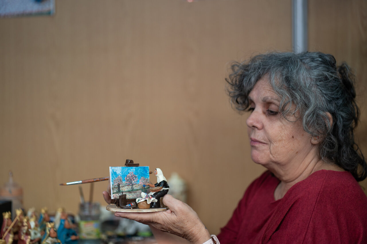 Mujer mostrando una figura artesanal en una feria navideña.