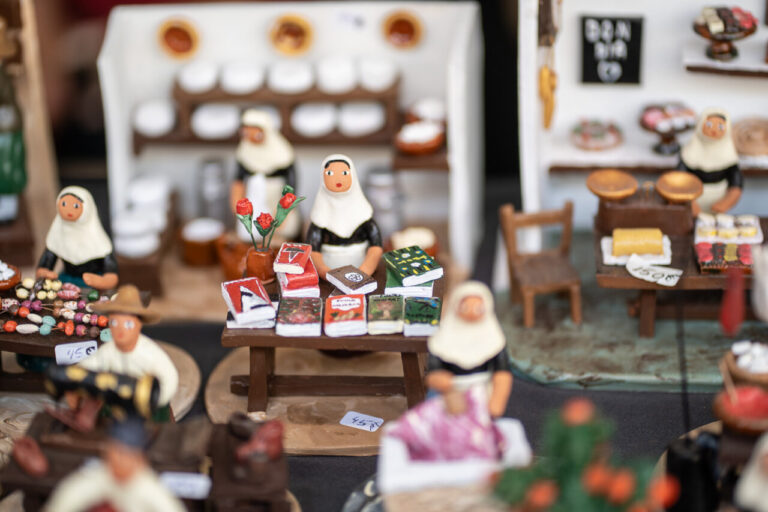 Figuras de artesanos en un mercado navideño con productos típicos.