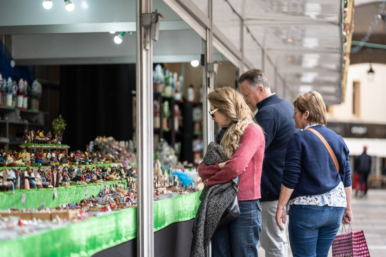 Personas observando artesanías en un mercado navideño.