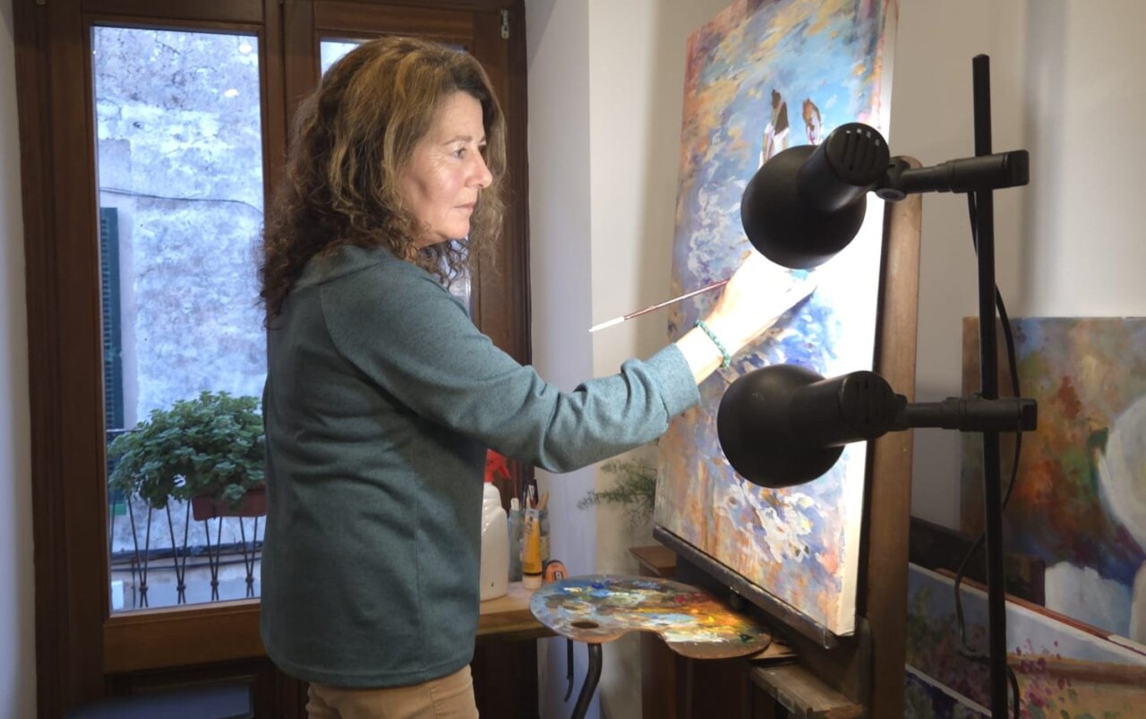 Dolors Martí pintando en su taller con un lienzo y paleta de colores.