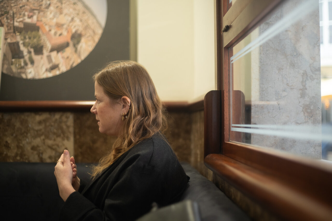 Mujer sentada en un sofá conversando en un entorno acogedor.