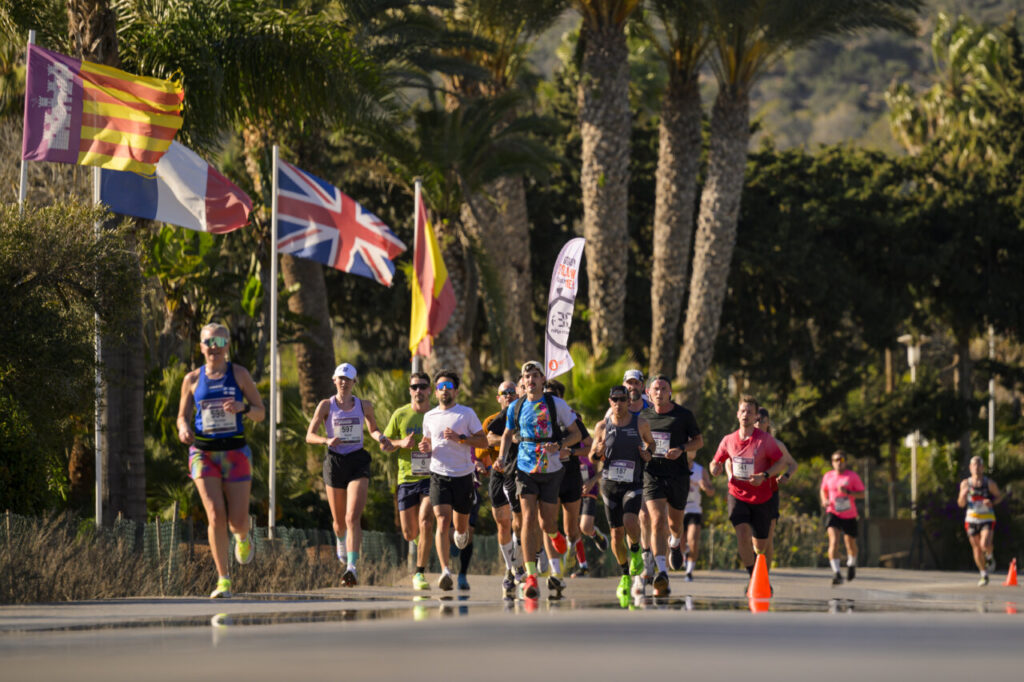 Corredores participando en la Half Marathon en Magaluf rodeados de banderas