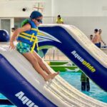 Ni&ntilde;o desliz&aacute;ndose por un tobog&aacute;n inflable en una piscina