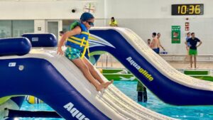 Ni&ntilde;o desliz&aacute;ndose por un tobog&aacute;n inflable en una piscina
