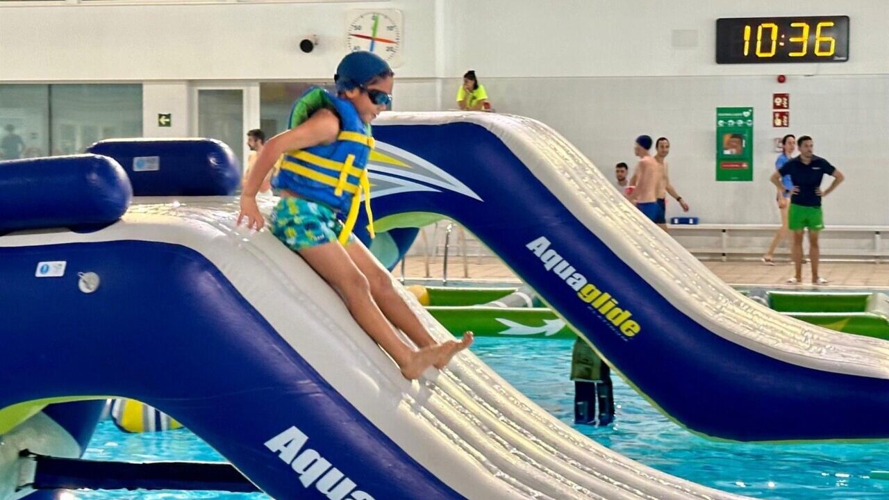 Ni&ntilde;o desliz&aacute;ndose por un tobog&aacute;n inflable en una piscina