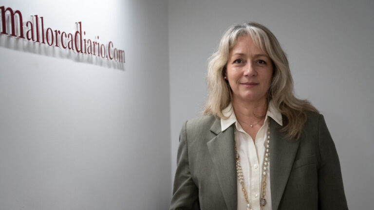 Mujer con chaqueta gris y collar de perlas en un entorno profesional