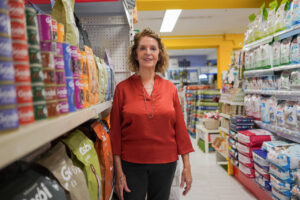 Mujer en una tienda de piensos rodeada de productos para mascotas.