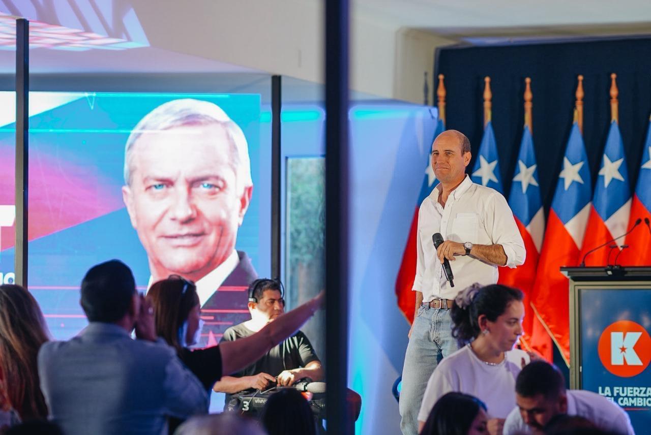 Mart&iacute;n Arrau en un evento pol&iacute;tico con banderas chilenas de fondo.