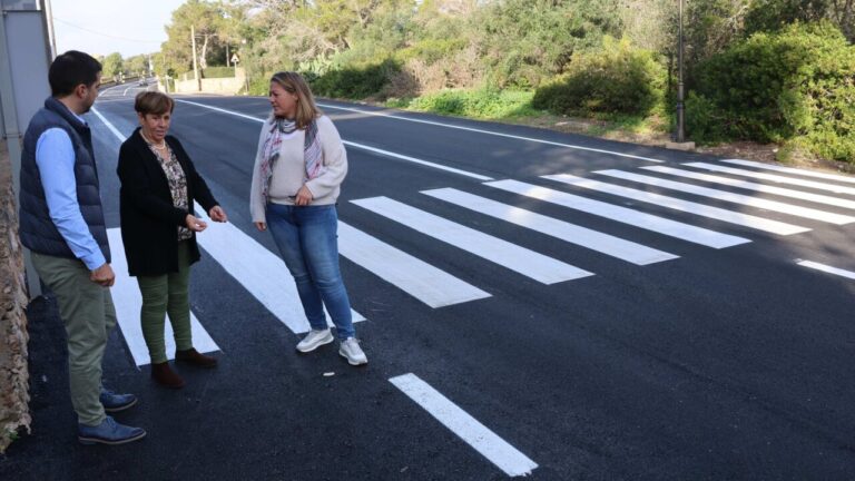 Tres personas observando la entrada asfaltada de Cala Figuera